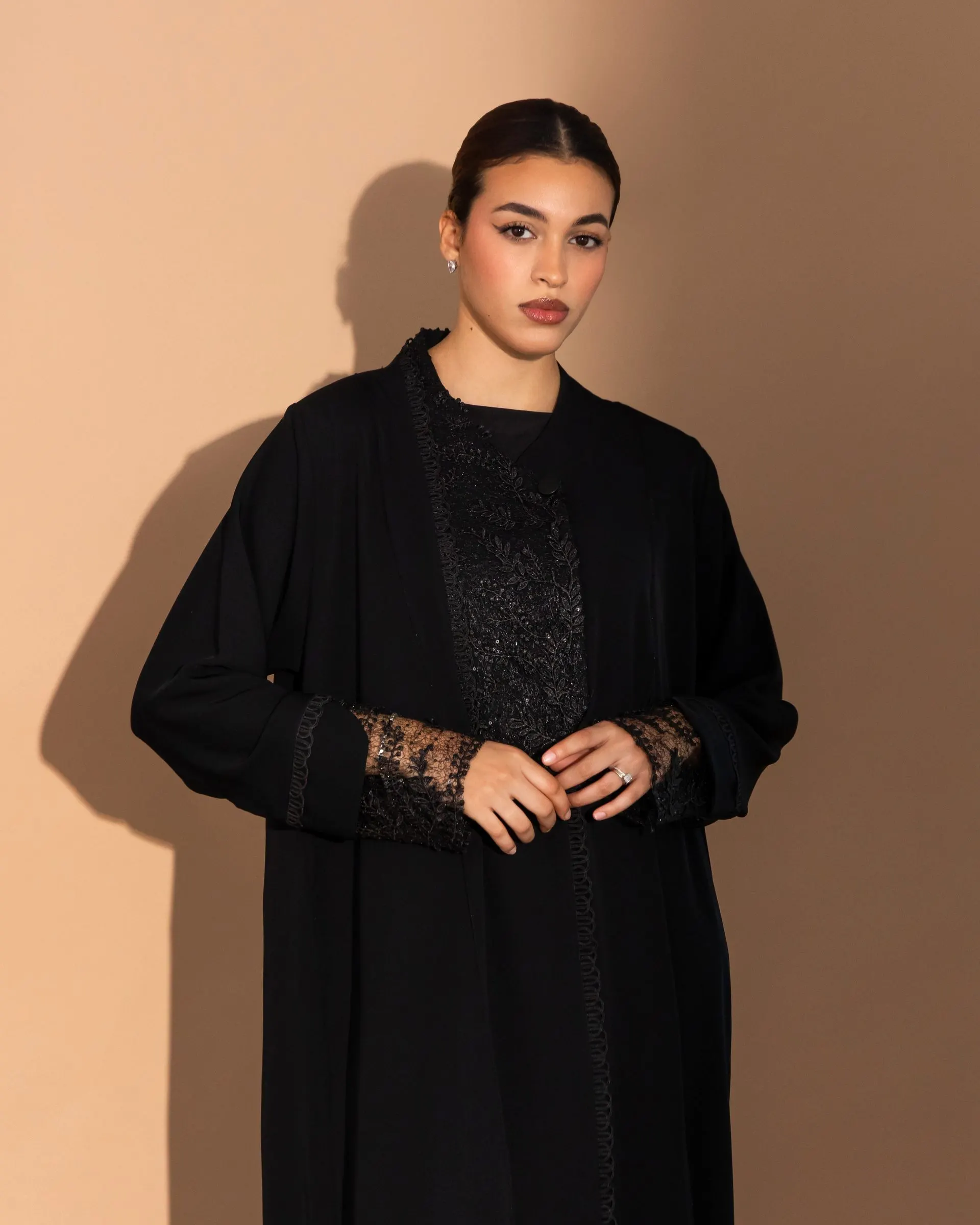 Dana Abaya lookbook: black lace abaya on a warm studio backdrop